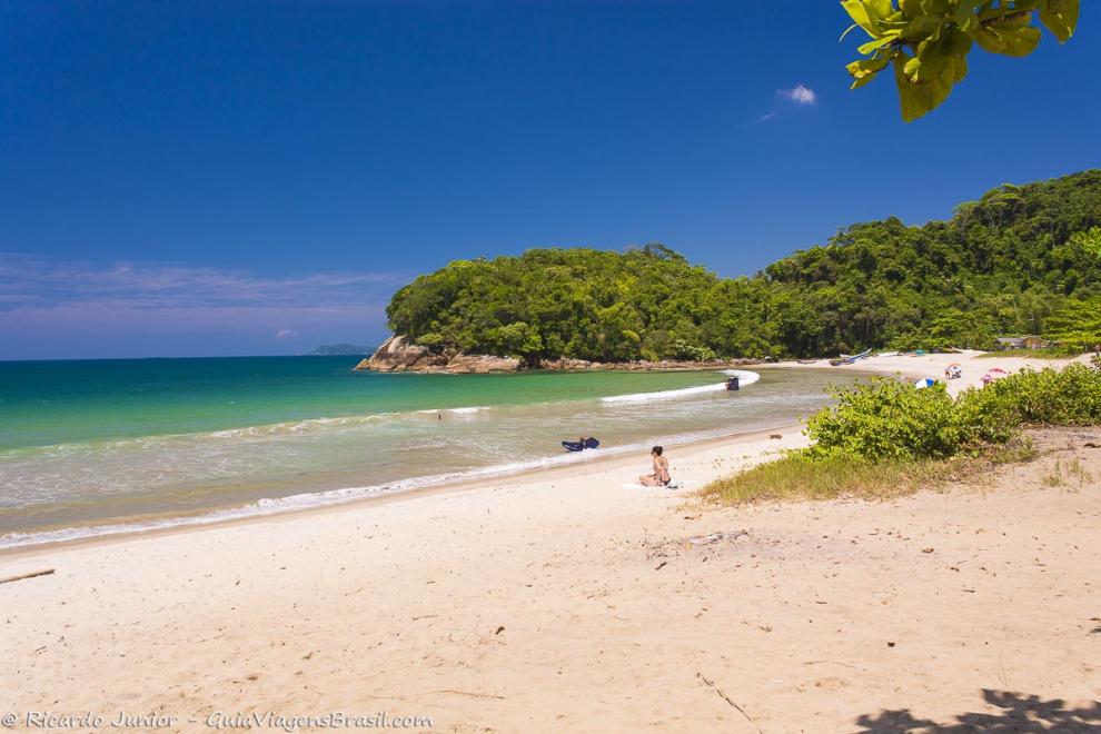 Imagem de uma moça sentada na areia da Praia de Camburi.